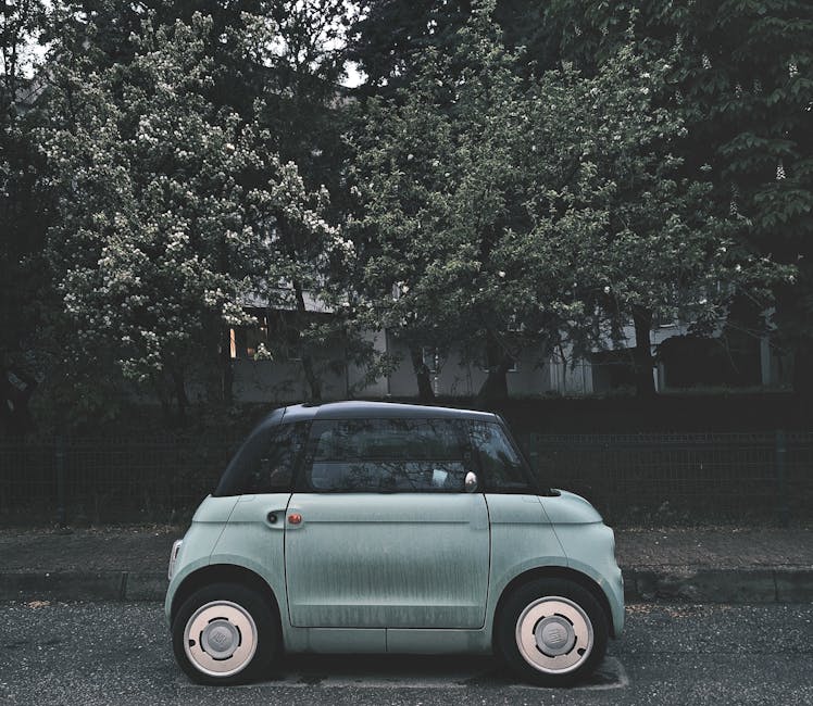A modern compact electric car parked under blooming trees on a city street, highlighting urban eco-friendly transportation.